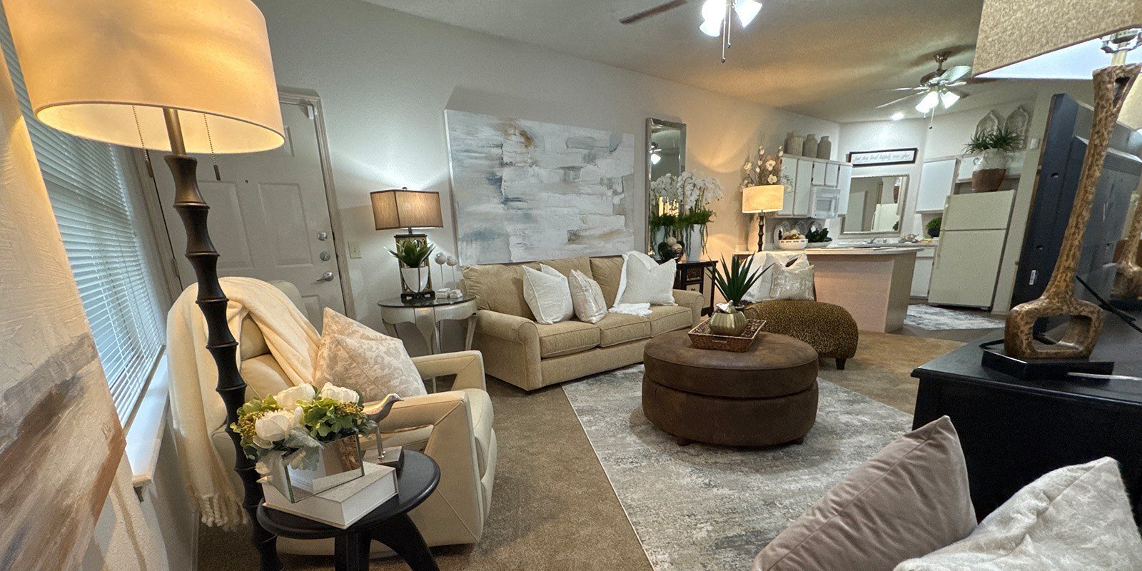 A living room with a white couch, a brown armchair, and a coffee table with a vase of flowers on it.
